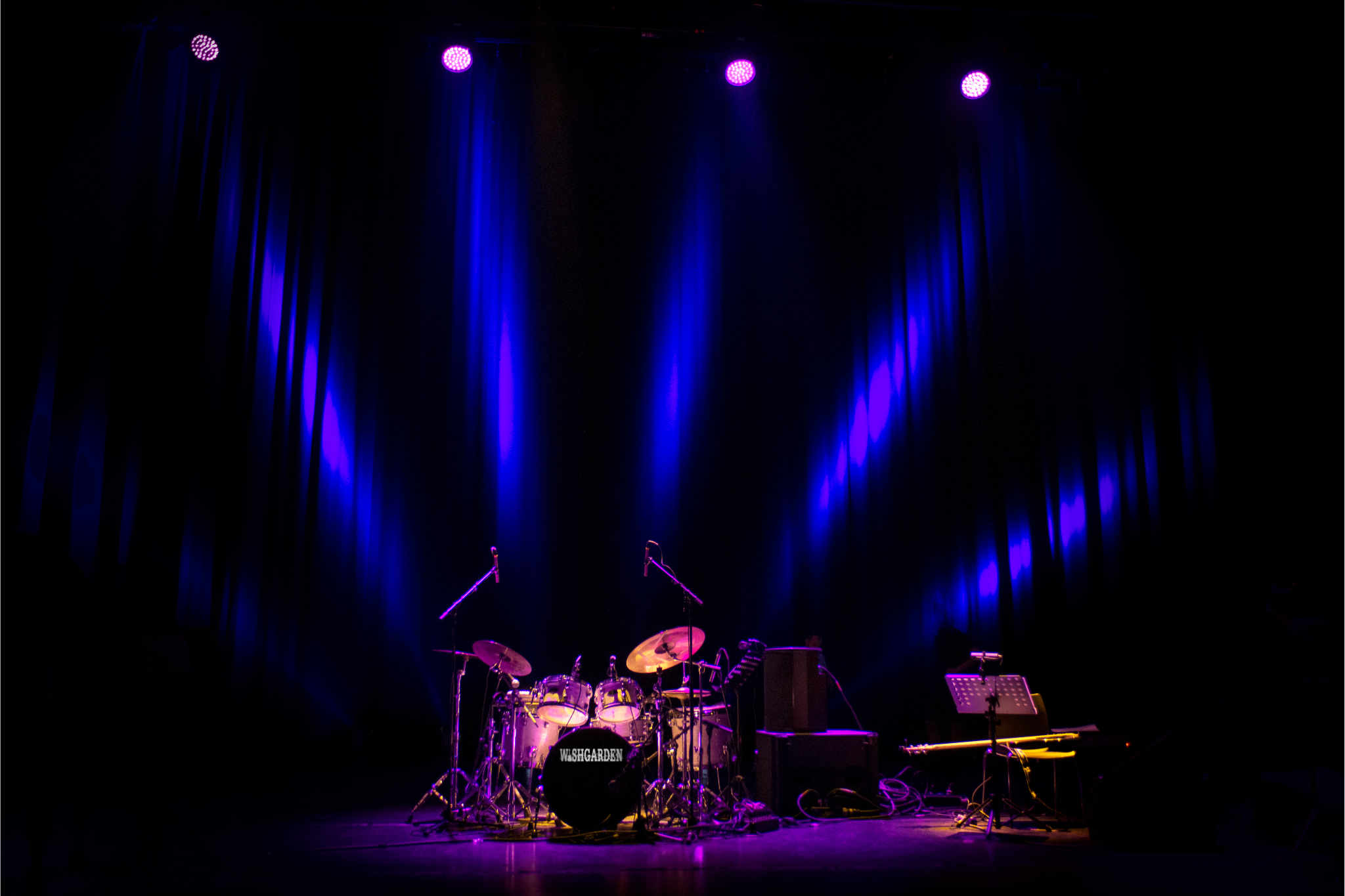Empty stage with lighted drum kit and spotlights shining down.