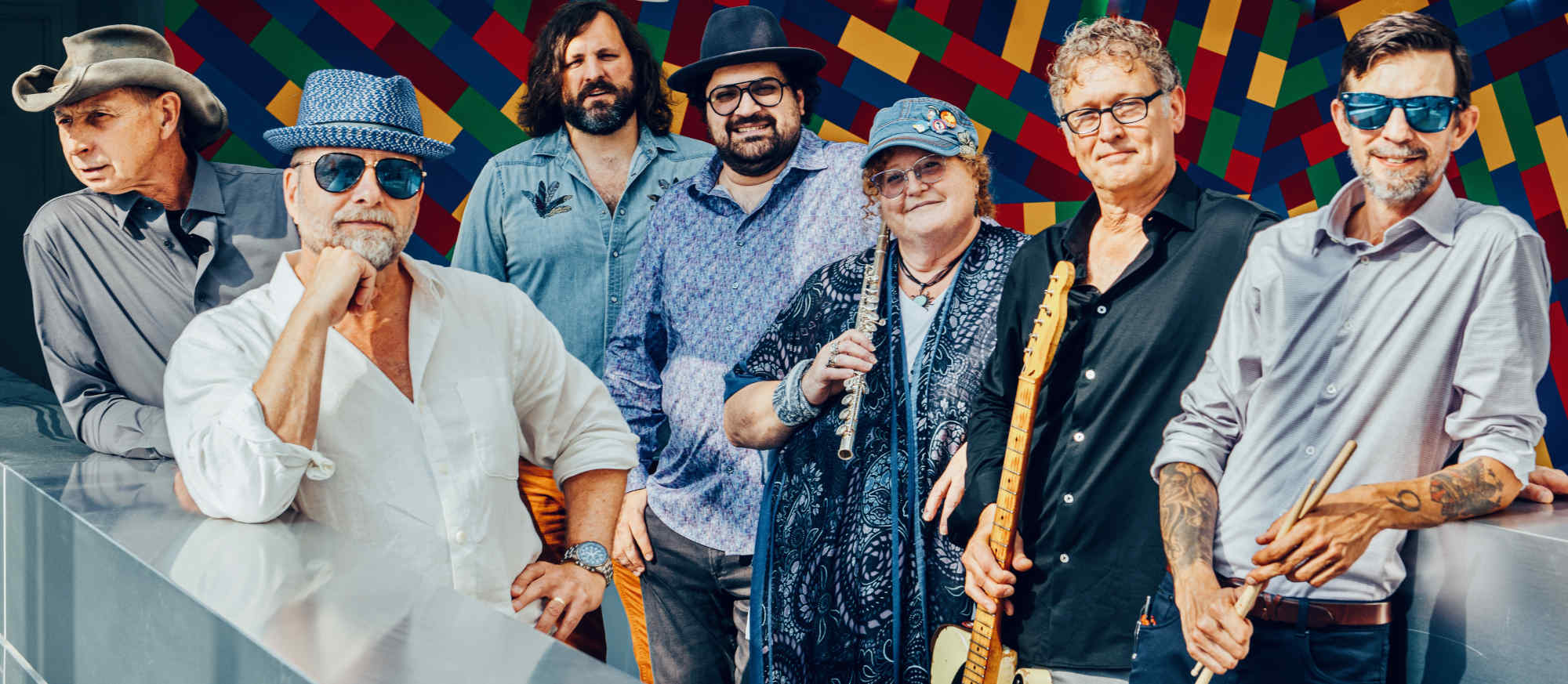 Full band, members lined up in a row, holding instruments.