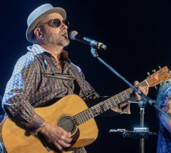 Wishgarden band leader Tony Paparello on stage at mic with guitar, singing.