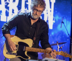 Mike Lenz, with electric guitar, onstage.